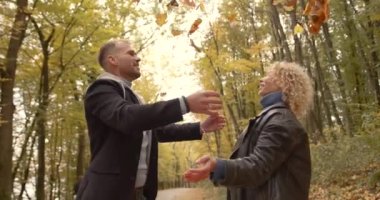 Romantic couple drops leaves and kisses in the park. Young people in outerwear lined up in the park