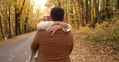 Beautiful couple man woman in love. Smiling laughing boyfriend and girlfriend hugging in park on autumn fall day. Togetherness and happiness. Authentic real people.