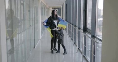 Ukrainian immigrants mother with daughter. They are holding Ukrainian flag.