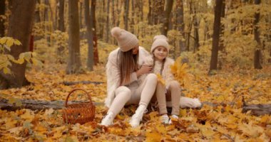 Mom and her daughter spending weekend, picnic in the autumn forest together. Mother and child relations.