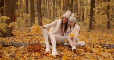 Mom and her daughter spending weekend, picnic in the autumn forest together. Mother and child relations.