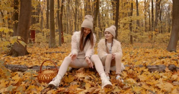 Mom and her daughter spending weekend, picnic in the autumn forest together. Mother and child relations.