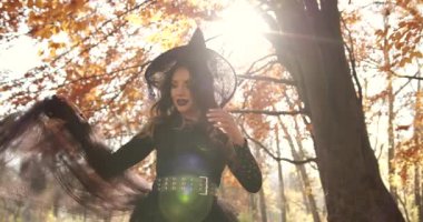 Beautiful brunette woman holding hands on a dress. She looks like a witch in a special dress and hat. Halloween style