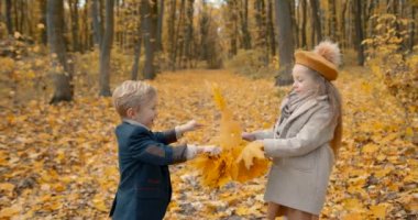 Cute little brother and sister playing on the weekend. Spending time in nature. Two schoolkids in a fall forest.