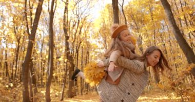 European woman with her school age daughter have time togther at autumn forest. Love, motherhood, school time concept.