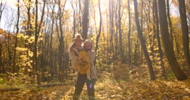 European woman with her school age daughter have time togther at autumn forest. Love, motherhood, school time concept.