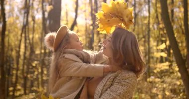 European woman with her school age daughter have time togther at autumn forest. Love, motherhood, school time concept.
