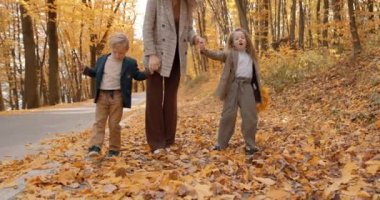 Family paying in autumn park. Mother with her son and dauther having a happy weekend together.