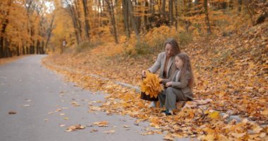 Happy mother with kid enjoying the weekend at park. Beautiful yellow autumn background. 4k.