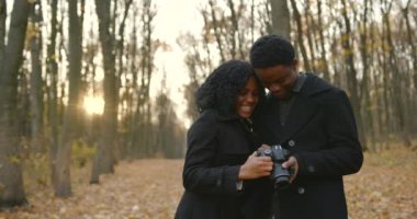 Boyfriend photographing his girlfriend in autumn park. Dating concept.