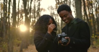 Boyfriend photographing his girlfriend in autumn park. Dating concept.