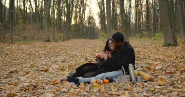 Autumn season. Young black people on a romantic date, hugging and reading a book.