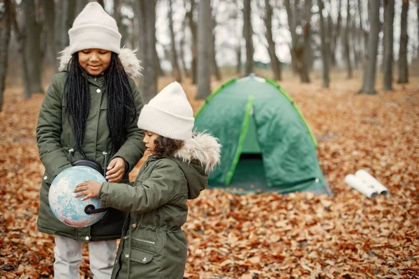 Ormanda kamp yapan güzel siyah kızlar. Sonbahar ormanında çadırda oturmuş haritaya bakan iki kız kardeş. Hakiki ceket giyen siyah kızlar..