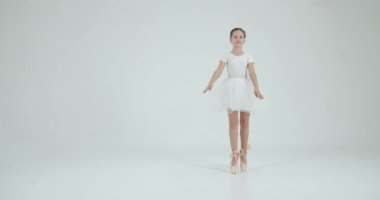 Beyaz etekli kız beyaz stüdyoda esniyor. Dans, balo okulu konsepti.