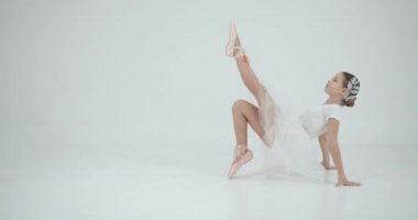 Beyaz etekli kız beyaz stüdyoda esniyor. Dans, balo okulu konsepti.