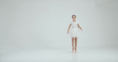 Beyaz etekli kız beyaz stüdyoda esniyor. Dans, balo okulu konsepti.