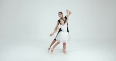 Genç öğretmenle gösteri yapan bir kız. Dans, bale konsepti. Beyaz stüdyo.