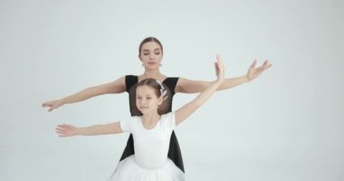 Genç öğretmenle gösteri yapan bir kız. Dans, bale konsepti. Beyaz stüdyo.