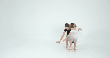 Genç öğretmenle gösteri yapan bir kız. Dans, bale konsepti. Beyaz stüdyo.