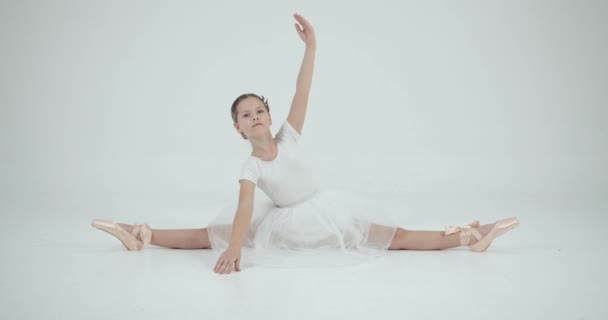 白のスタジオでストレッチ白のチュチュの女の子 ダンス 社交ダンススクールのコンセプト — ストック動画