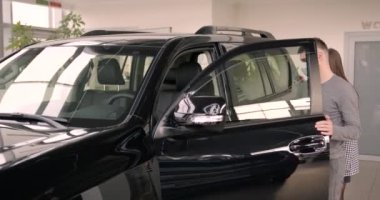 Yüzlerinde koruyucu maske olan genç bir çift. Araba galerisinden yeni bir araba almak..