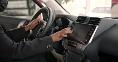 Maskeli kadın, modern arabanın içini incelerken, içeride oturuyordu. Kadın araba galerisinde yeni bir araba seçiyor. Koruyucu önlemler, covid-19.