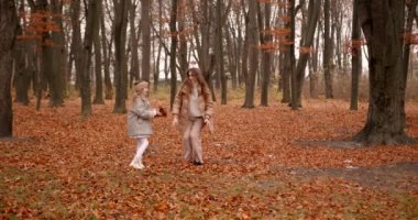 Annesiyle ormanda oynayan sevimli küçük bir kız. Sonbahar mevsimi.