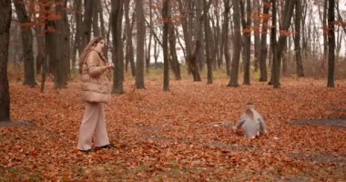 Annesiyle ormanda oynayan sevimli küçük bir kız. Sonbahar mevsimi.