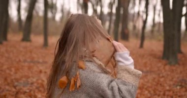 Saçları dökülen yapraklı bir çocuk. Sonbahar ormanı geçmişi.