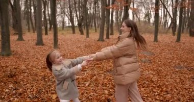 Anne ve kızının mutlu ailesi sonbahar ormanında dönüyorlar. Anne ve çocuk hafta sonları birlikte vakit geçiriyorlar..