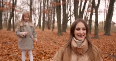 Kızı, sonbahar ormanında anasına yaklaşıyor. Kızlar birlikte vakit geçiriyorlar. Mutlu çocukluk ve annelik kavramı.