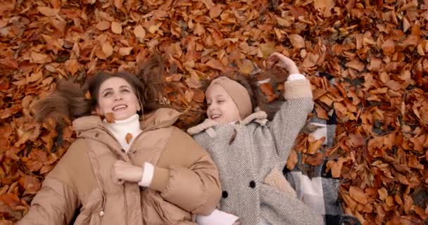 母亲和孩子躺在落叶上笑着 — 图库视频影像