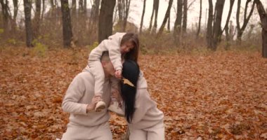 Sonbahar parkında aile eğleniyor. Genç ebeveynler ve küçük kız hafta sonları birlikte vakit geçiriyorlar. Sonbahar sezonu.