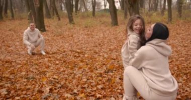 Sonbahar parkında aile eğleniyor. Genç ebeveynler ve küçük kız hafta sonları birlikte vakit geçiriyorlar. Sonbahar sezonu.