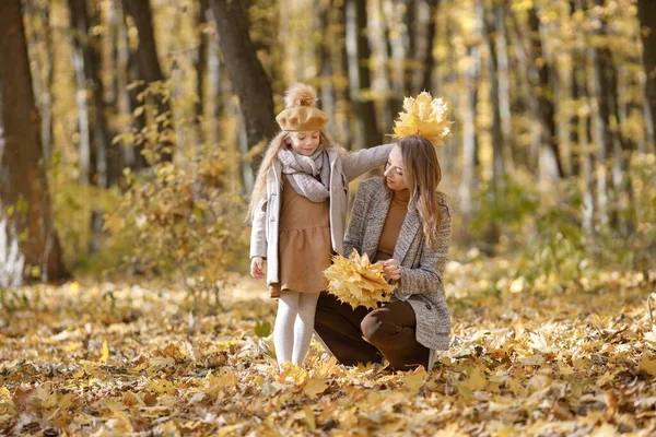 秋の森の中の若い女性と少女 黄色の葉を持つ娘の近くの女性 ファッションの服を着た女の子 — ストック写真