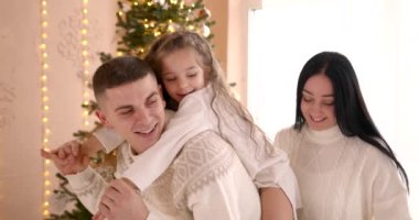 Mutlu aile Noel ağacının yanında eğleniyor. Baba kızıyla oynuyor, hediyeleri açıyor. Kış tatili kavramı.