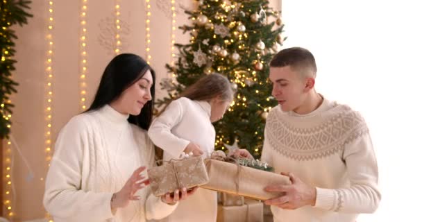 幸せな家族はクリスマスツリーの近くで一緒に楽しんでいます 父親の娘と遊んで 贈り物をアンパック 冬休みのコンセプト — ストック動画