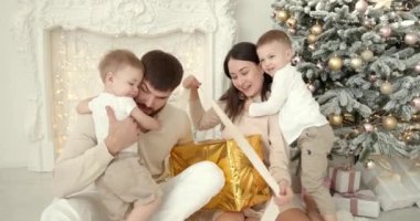 Neşeli genç ebeveynler ve sevimli küçük oğullar Noel 'i kutluyor ve eğleniyorlar. Aile tatilleri. Çocukluk kavramı.
