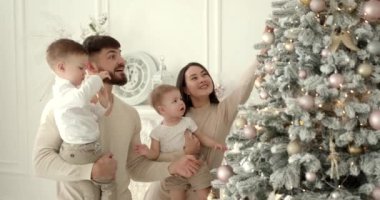 Mutlu aile yeni yıl kutlamaları için hazırlanıyor. Noel ağacı süslemek, modern konforlu evde neşeli bir atmosfer yaratmak..