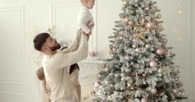 Mutlu aile yeni yıl kutlamaları için hazırlanıyor. Noel ağacı süslemek, modern konforlu evde neşeli bir atmosfer yaratmak..