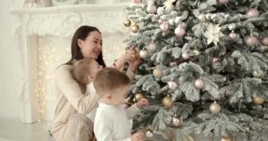 Mutlu aile yeni yıl kutlamaları için hazırlanıyor. Noel ağacı süslemek, modern konforlu evde neşeli bir atmosfer yaratmak..