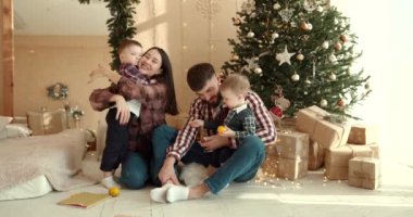 Neşeli genç ebeveynler ve sevimli küçük oğullar Noel 'i kutluyor ve eğleniyorlar. Aile tatilleri. Çocukluk kavramı.