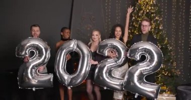 Yeni yıl 2022 kavramı. Bir grup neşeli genç elinde balonlarla yeni yılı kutluyor ve eğleniyor..