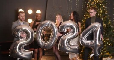 Yeni yıl 2024 konsepti. Bir grup neşeli genç ellerinde balonlar, şirket partileri....