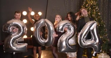 Yeni yıl 2024 konsepti. Bir grup neşeli genç ellerinde balonlar, şirket partileri....