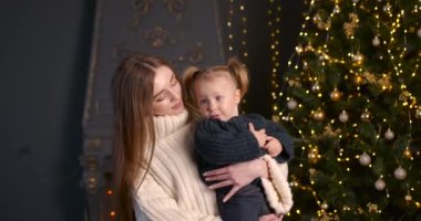 Ebeveyn ve küçük çocuk içeride noel ağacının yanında birlikte oynuyorlar. Mutlu noeller ve mutlu tatiller. Neşeli anne ve tatlı kızı.