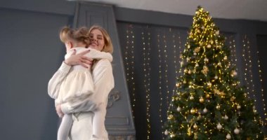 Ebeveyn ve küçük çocuk içeride noel ağacının yanında birlikte oynuyorlar. Mutlu noeller ve mutlu tatiller. Neşeli anne ve tatlı kızı.