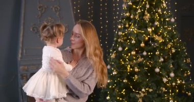 Ebeveyn ve küçük çocuk içeride noel ağacının yanında birlikte oynuyorlar. Mutlu noeller ve mutlu tatiller. Neşeli anne ve tatlı kızı.