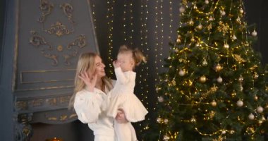 Ebeveyn ve küçük çocuk içeride noel ağacının yanında birlikte oynuyorlar. Mutlu noeller ve mutlu tatiller. Neşeli anne ve tatlı kızı.