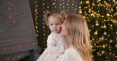 Ebeveyn ve küçük çocuk içeride noel ağacının yanında birlikte oynuyorlar. Mutlu noeller ve mutlu tatiller. Neşeli anne ve tatlı kızı.